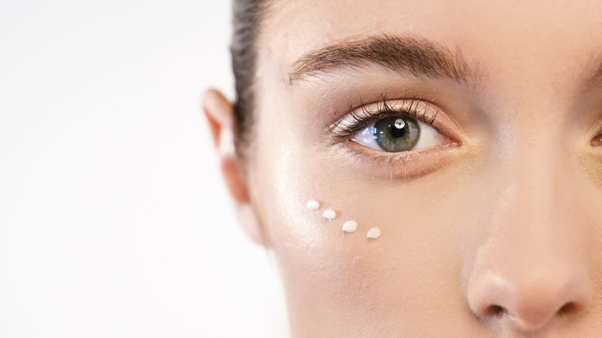 Close up of woman's skin with dots of skincare cream along contour of one eye