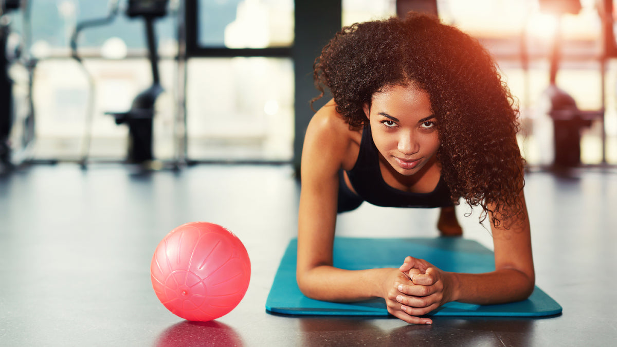 black woman doing a plank at the gym