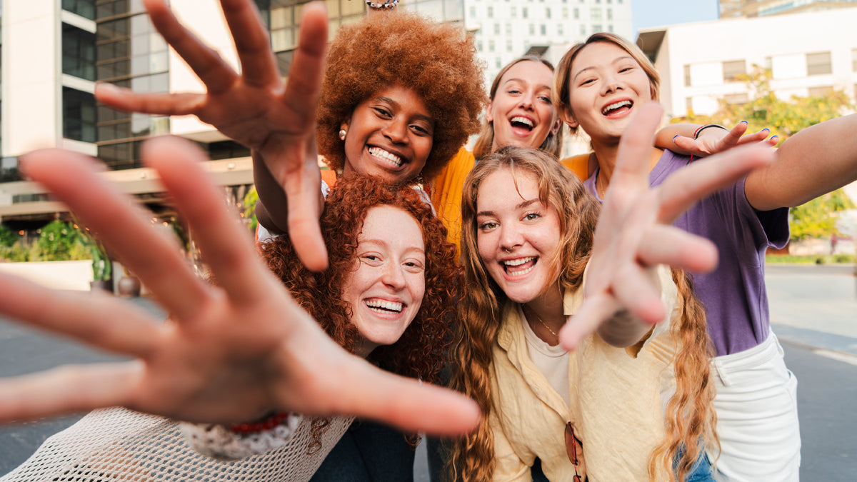 group of mixed female friends taking group selfie in sunshine