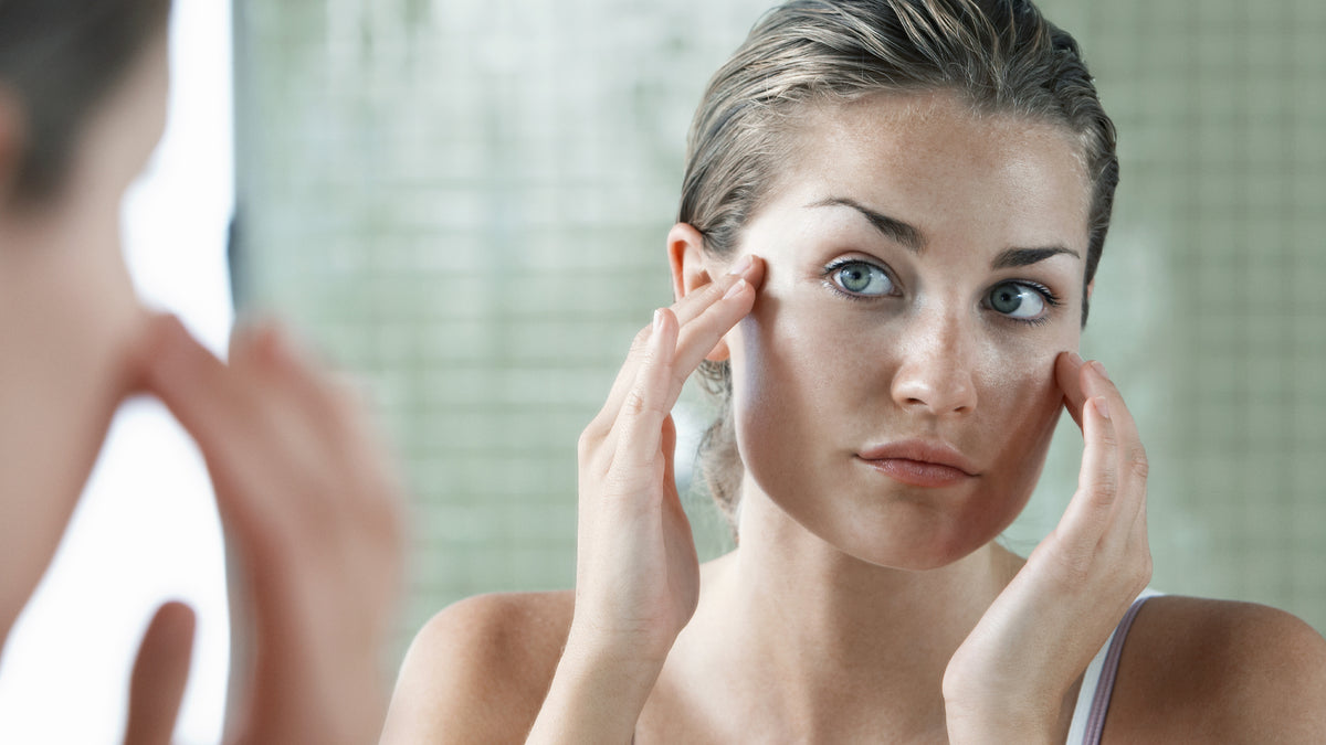 young woman looking at skin in the mirror