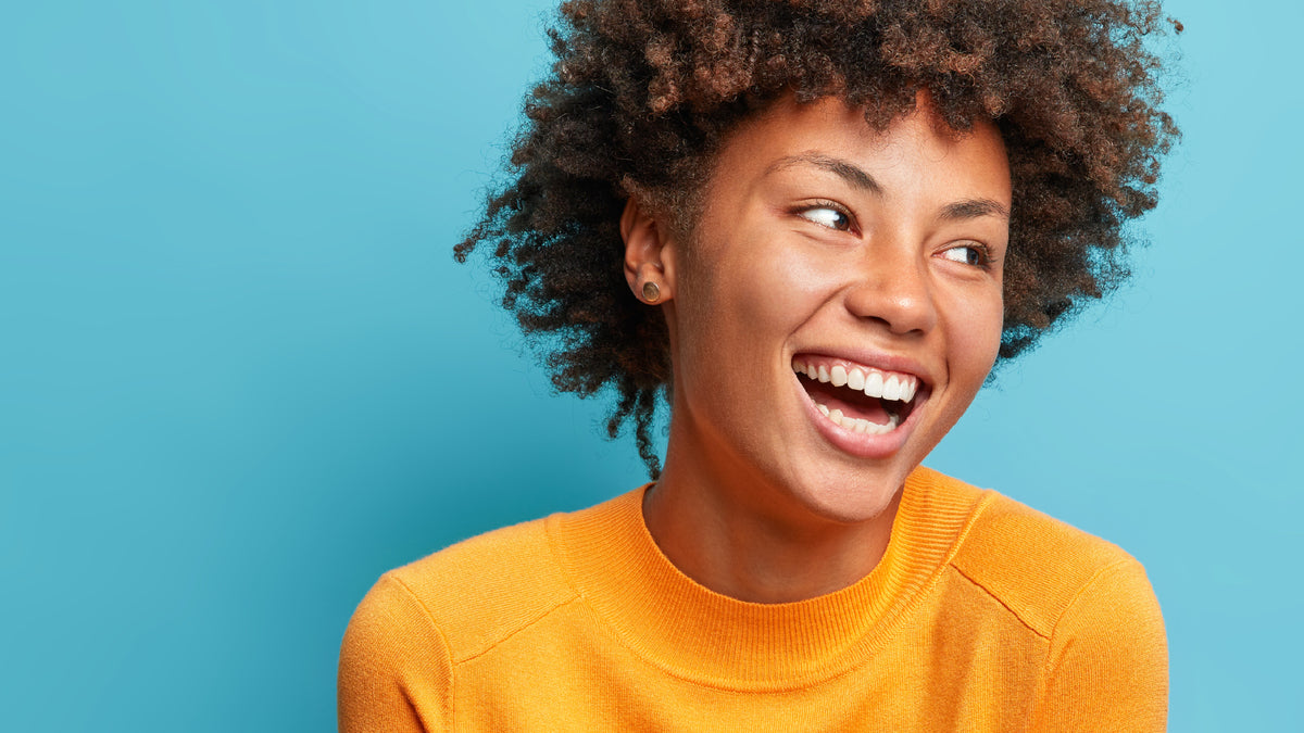 black girl with great skin laughing on blue background