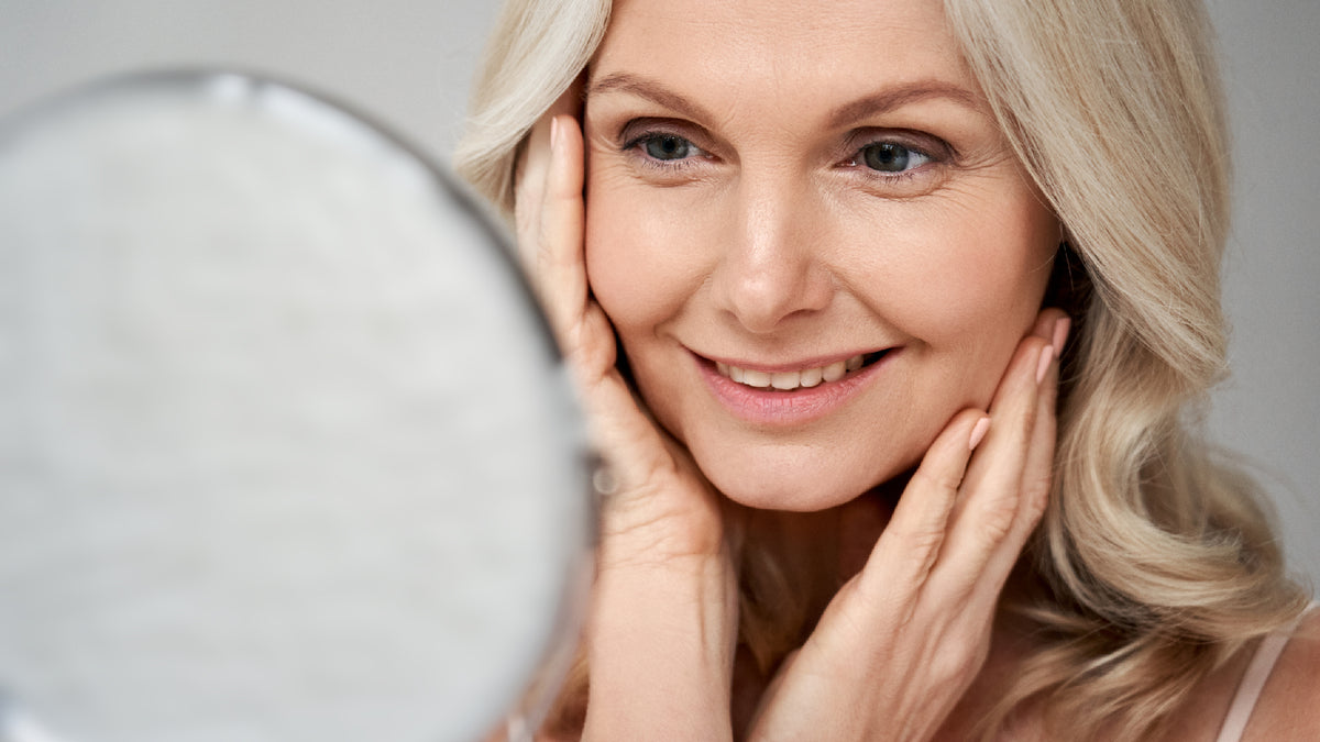 mature woman in mirror applying serum