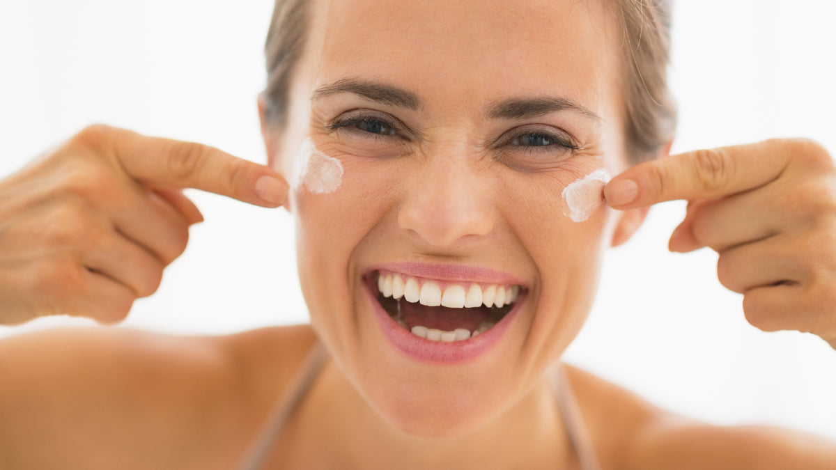 caucasian young woman laughing while applying face cream