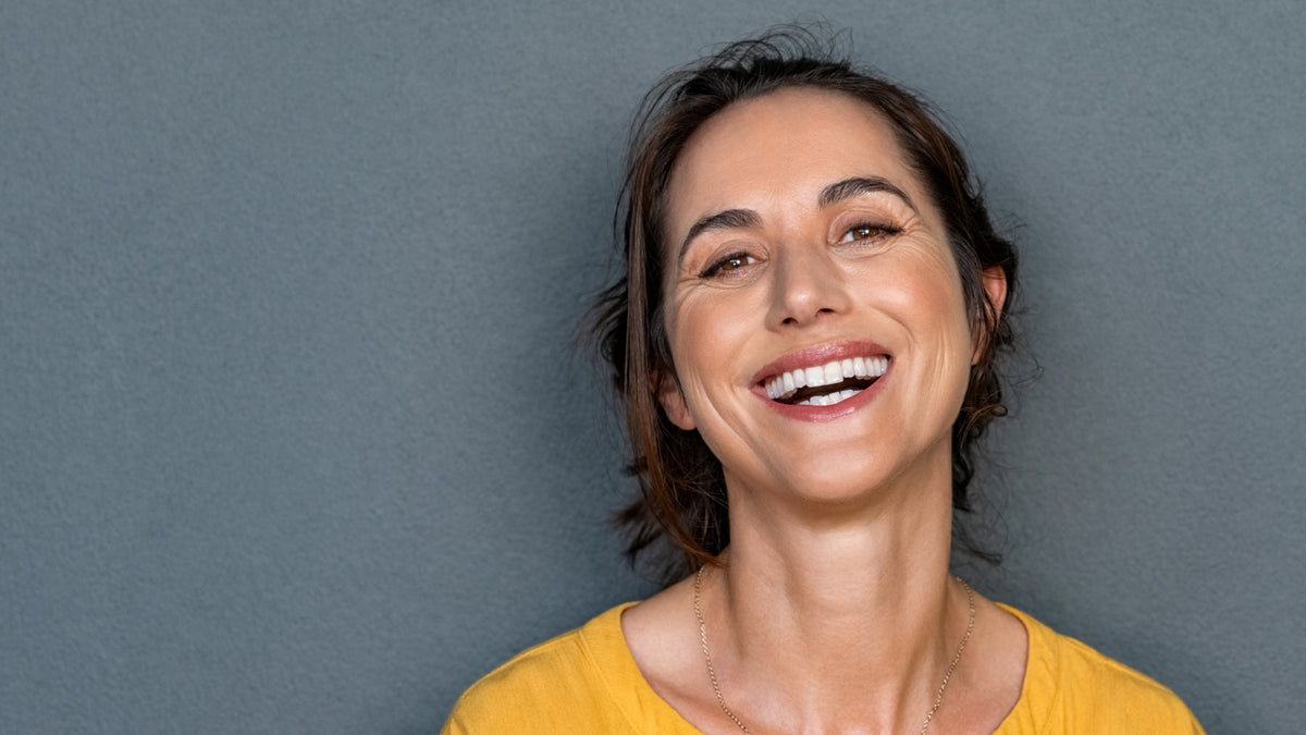 beautiful brunette woman smiling on gray background