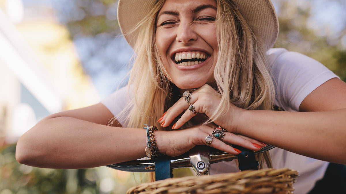 blonde young woman laughing on bicycle