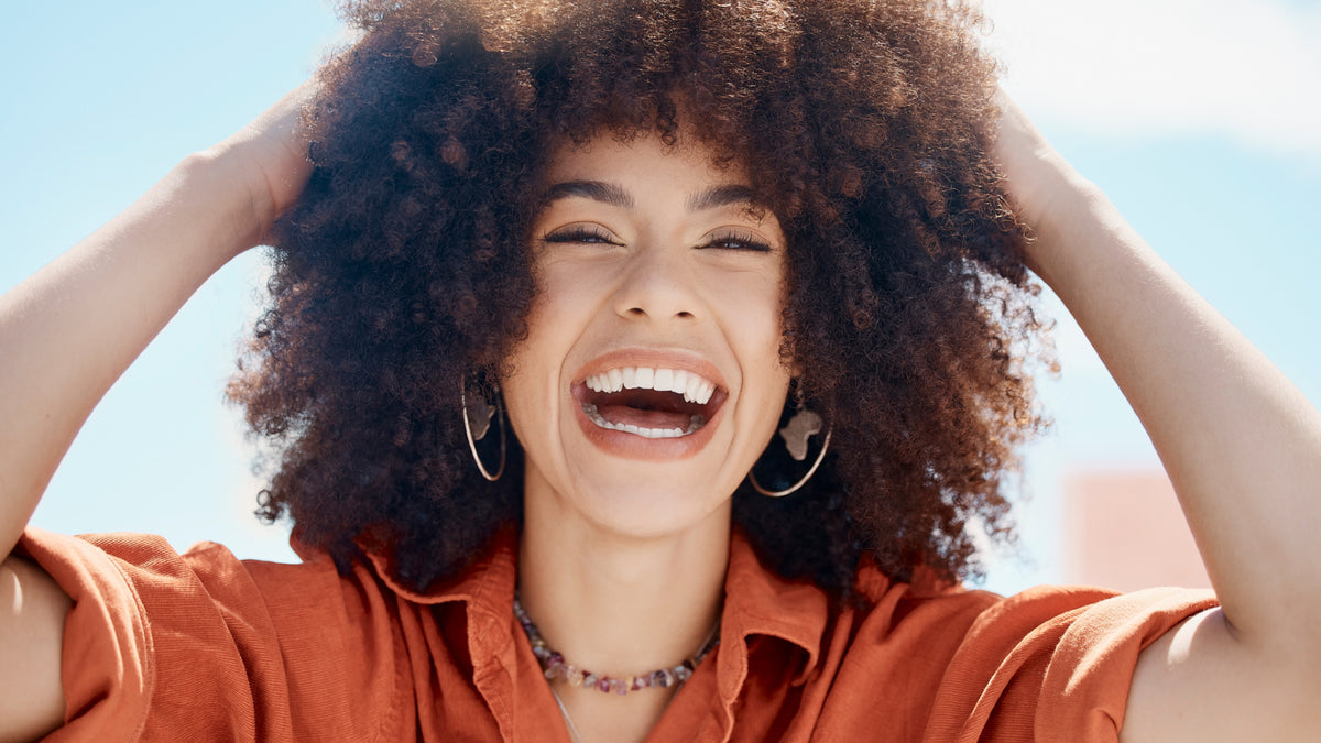 young woman outside laughing hands in hair