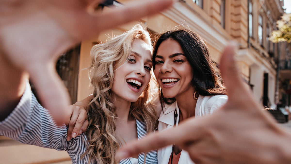 two girlfriends taking selfie together in the street