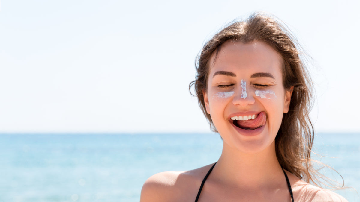 brunette girl on beach with sunscreen on face