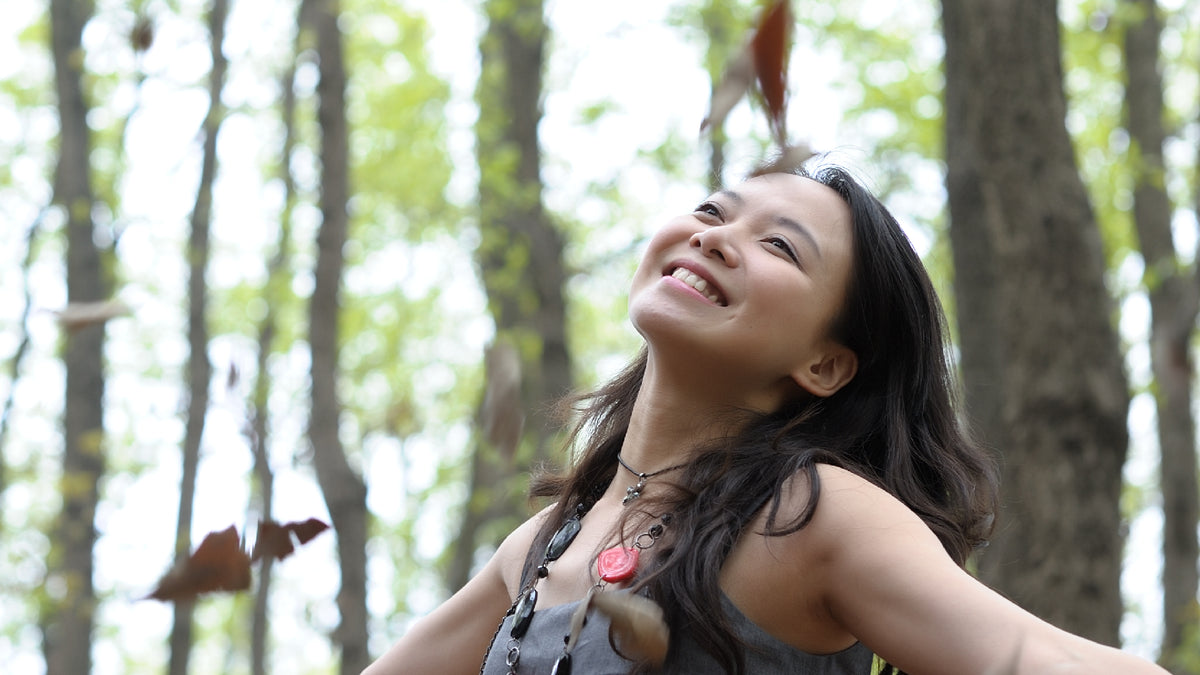Asian girl smiling and embracing nature with trees in backgroud