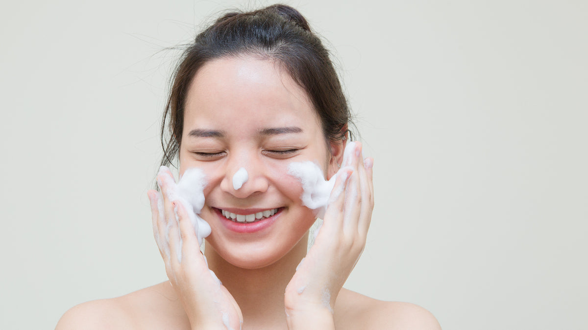 Asian teenager cleansing face, eyes closed
