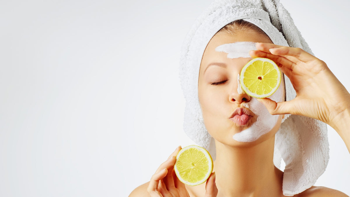 young woman with towel on head blowing kiss and holding lemons
