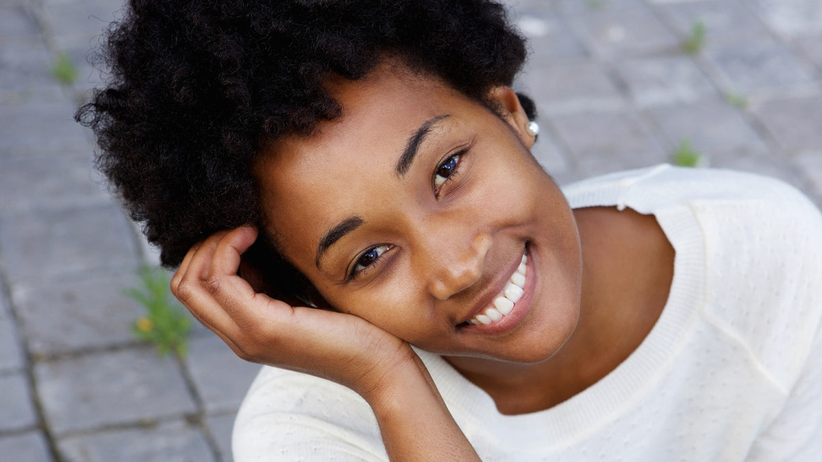 young black woman outside, smiling at camera 