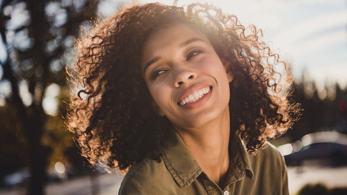 black girl with awesome hair and skin smiling outside