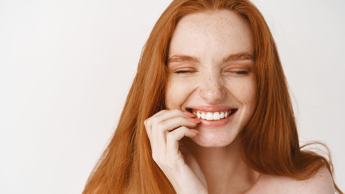 beautiful redhead with great skin touching face