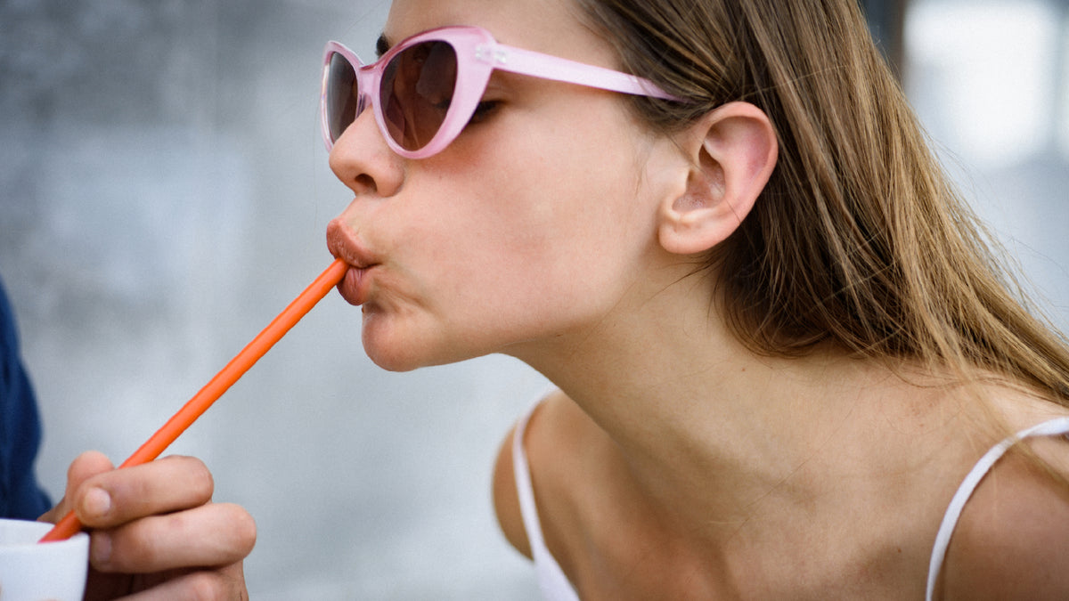 young woman drinking from a straw