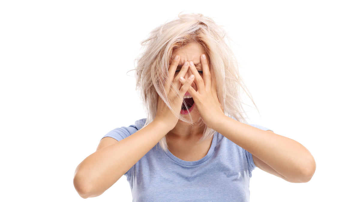 blonde woman with head covered by hands, screaming